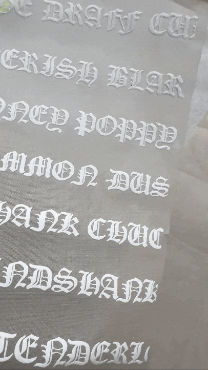 Automated embroidery machine stitching a gold floral pattern onto sheer black fabric.