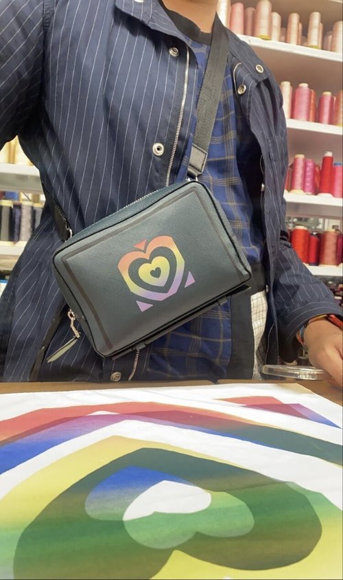 Close-up of a fabric bag with a heart-shaped reflective design that shifts in color under direct light.