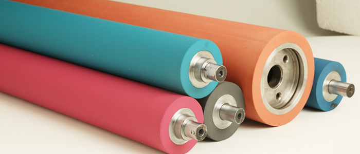 Set of colorful industrial rubber rollers in teal, pink, orange, and blue, each with metal cores and end shafts.