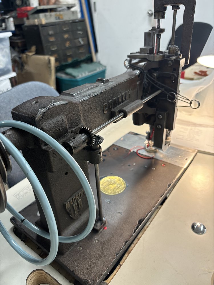 Brass label plate on a vintage Cornely embroidery machine, engraved with multilingual patent details and the maker’s name from Paris.