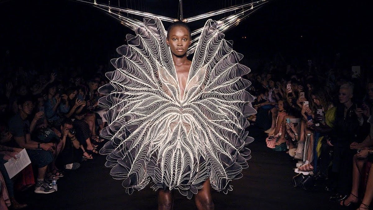 Runway look featuring a large circular dress made of layered, radiating translucent lines.