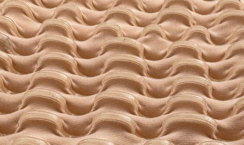 Fabric manipulated into a grid of sculptural, raised puckers in a fleshy nude tone.