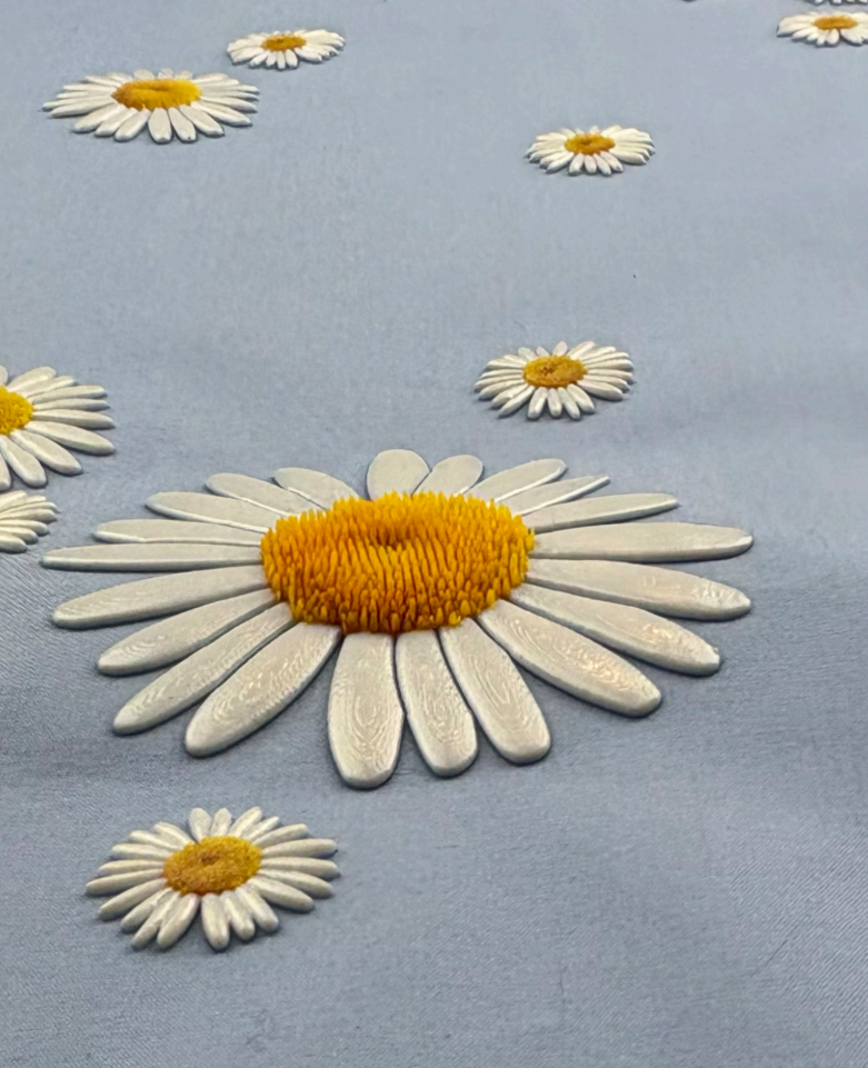 Embroidered daisies on blue fabric.