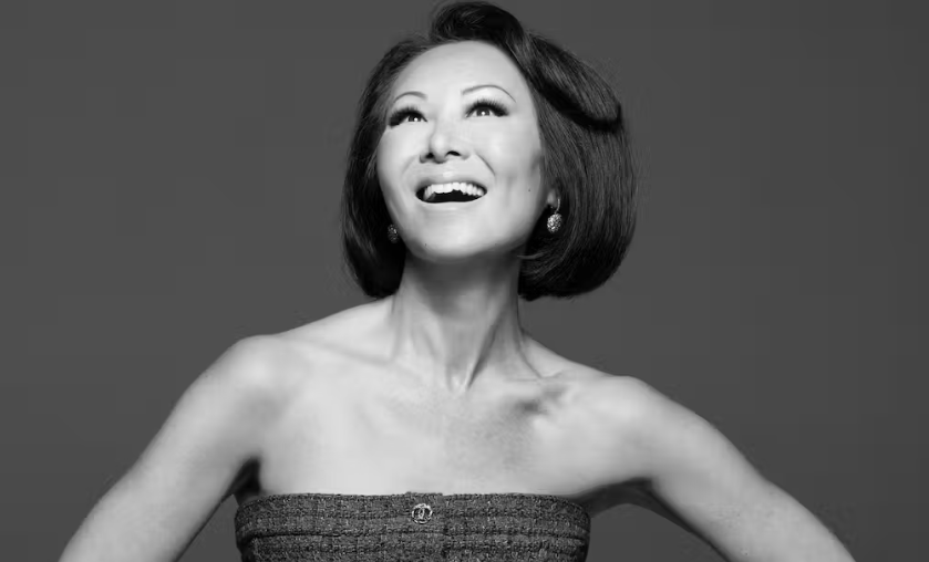 Woman in strapless dress smiling and looking up in joyful black-and-white portrait.