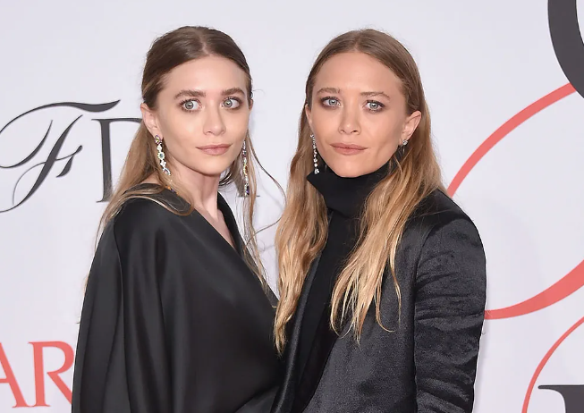 Mary-Kate and Ashley Olsen in black ensembles posing at CFDA Fashion Awards.