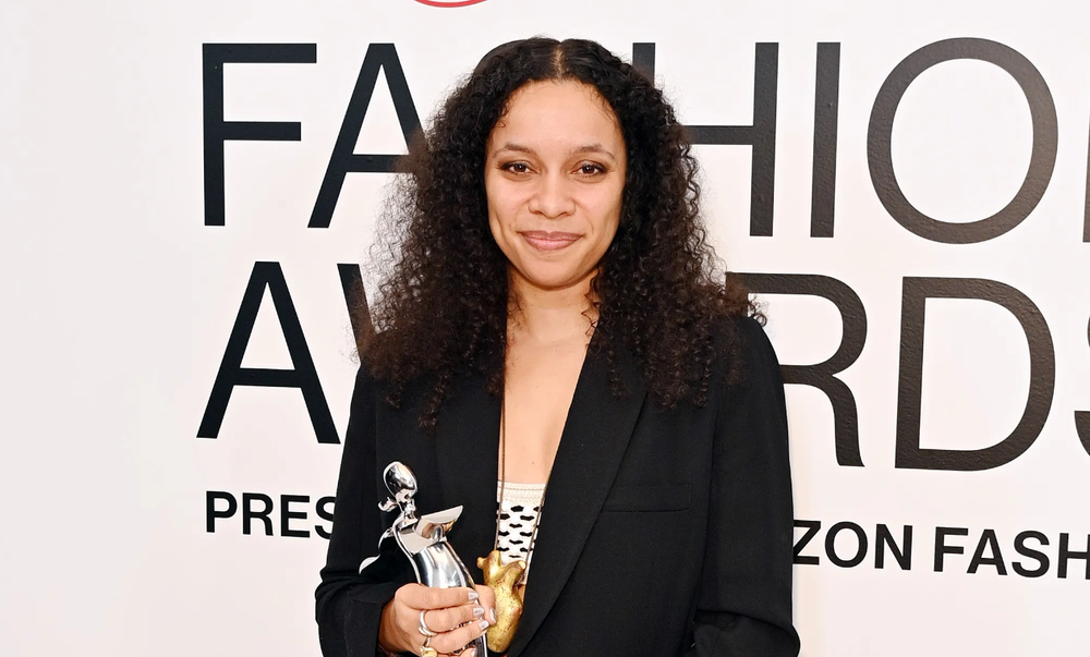 Woman in blazer holding CFDA award on red carpet.