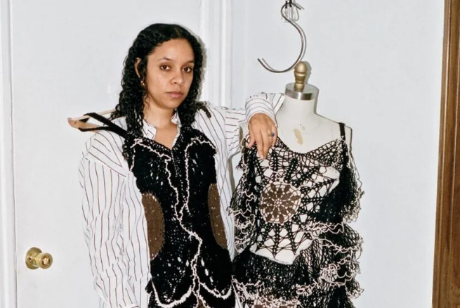 Woman stands next to mannequin dressed in black and white crochet ensemble.