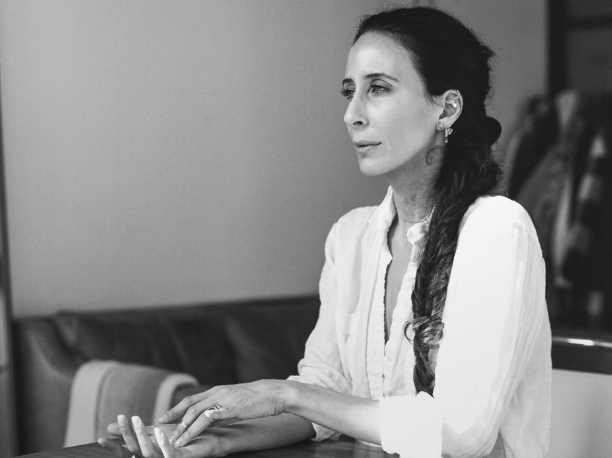 Woman in white button-down sitting at a desk, deep in thought.