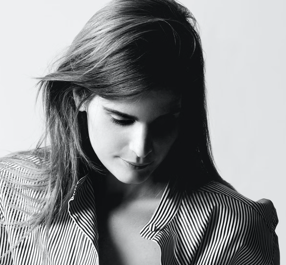 Woman in a striped shirt looking down in a soft, monochrome portrait.