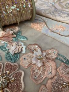 Embroidered floral tulle with threads and sequins arranged around it.