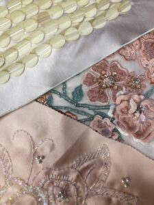 Embroidered floral tulle with threads and sequins arranged around it.