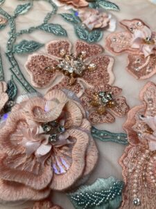 Embroidered floral tulle with threads and sequins arranged around it.