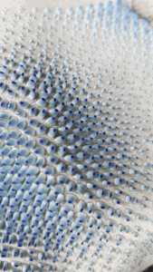 Close-up of white fabric with blue-gradient raised bubble texture.