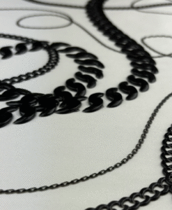 Black chain motifs embroidered on white fabric.