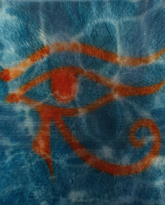 Fabric with a red Eye of Horus symbol painted over a rippling blue background resembling water.