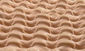 Fabric manipulated into a grid of sculptural, raised puckers in a fleshy nude tone.