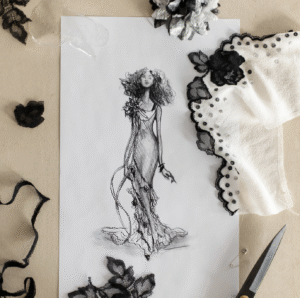 Fashion sketch of a gown surrounded by floral lace samples and black ribbon.