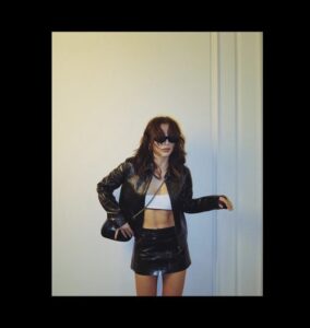 Woman in a black leather jacket and mini skirt with white bralette