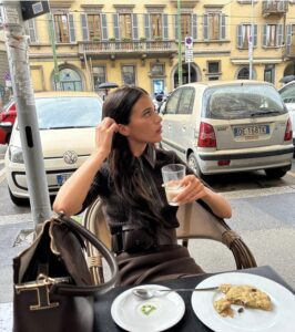 Woman in brown outfit at a café with a croissant and a drink