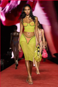 Female model in a sheer neon green outfit walking on the runway
