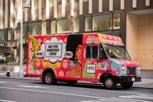 Brightly colored NYES van featuring pop art design parked on a city street.