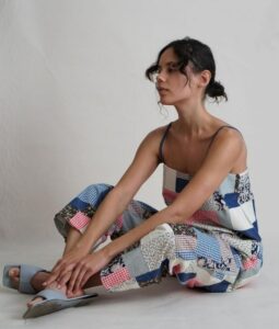 Woman seated in a strappy patchwork set in pastel blues, pinks, and prints.