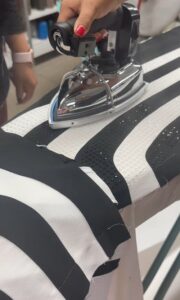 A person ironing a black and white striped fabric embedded with rhinestones.