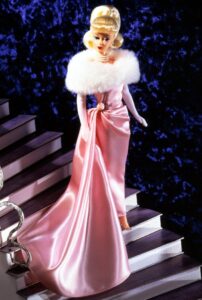 Barbie doll wearing a glamorous pink satin gown with fur shawl, standing on a staircase.