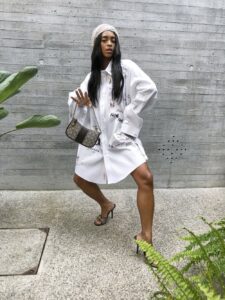 Woman wearing oversized white shirt as a dress, styled with heels and mini bag.