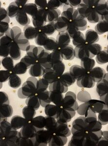 3D black floral embellishments with gold centers on translucent fabric.