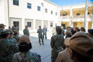 Group of military members gathered in a courtyard during a briefing.