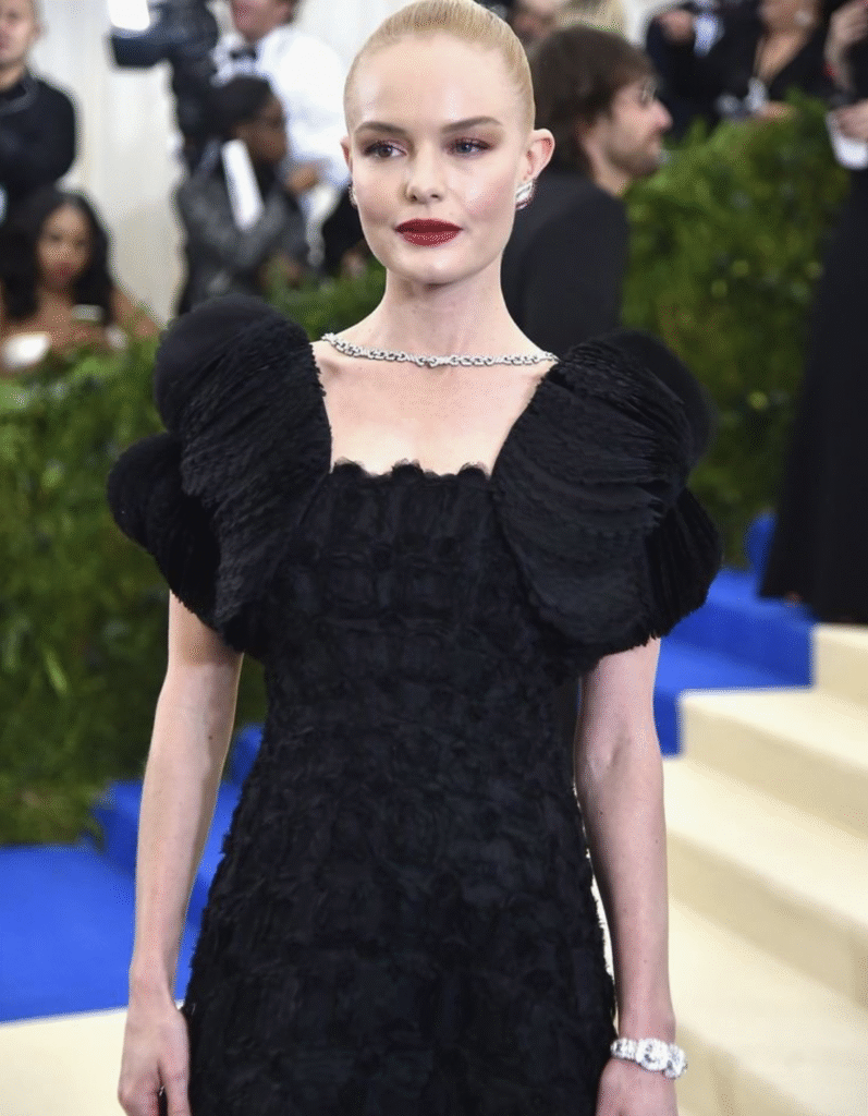 Kate Bosworth at the Met Gala wearing a dramatic black dress with puffed sleeves and detailed texture.