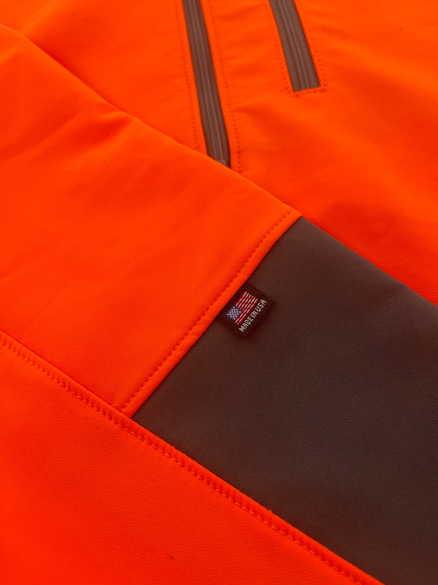 Close-up of orange and brown high-visibility garment with visible stitching and label.