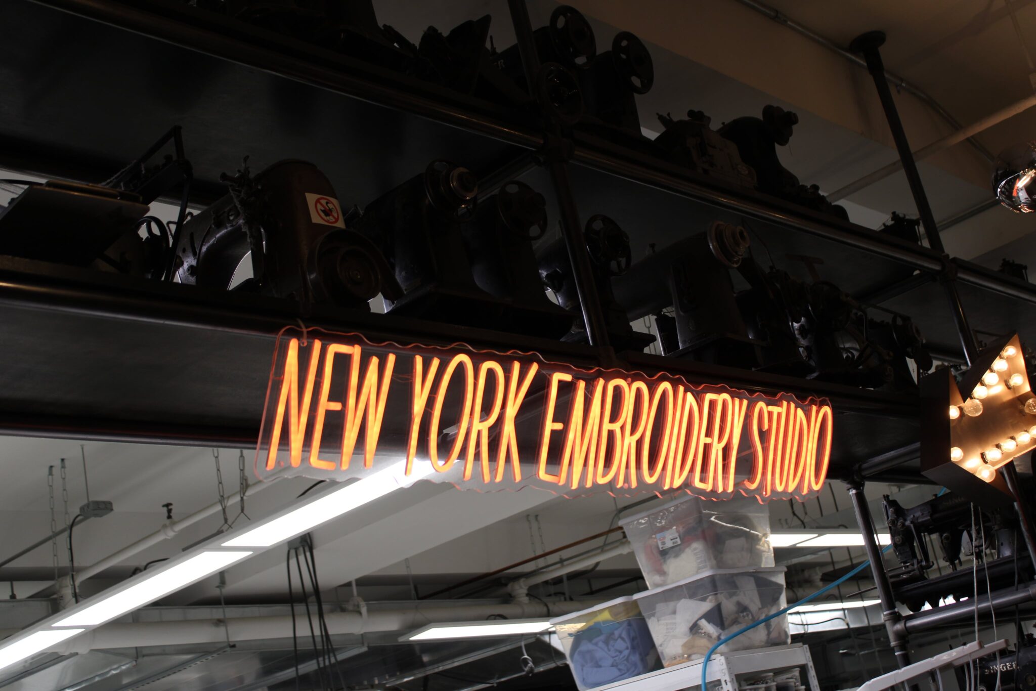 Neon sign that reads "New York Embroidery Studio" in an industrial space.