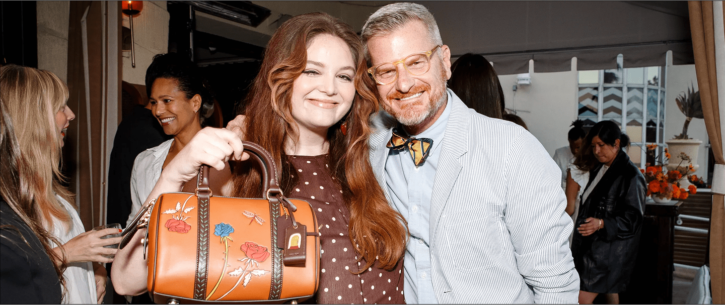 Woman holding a floral-embellished leather bag standing next to a smiling man in formal wear