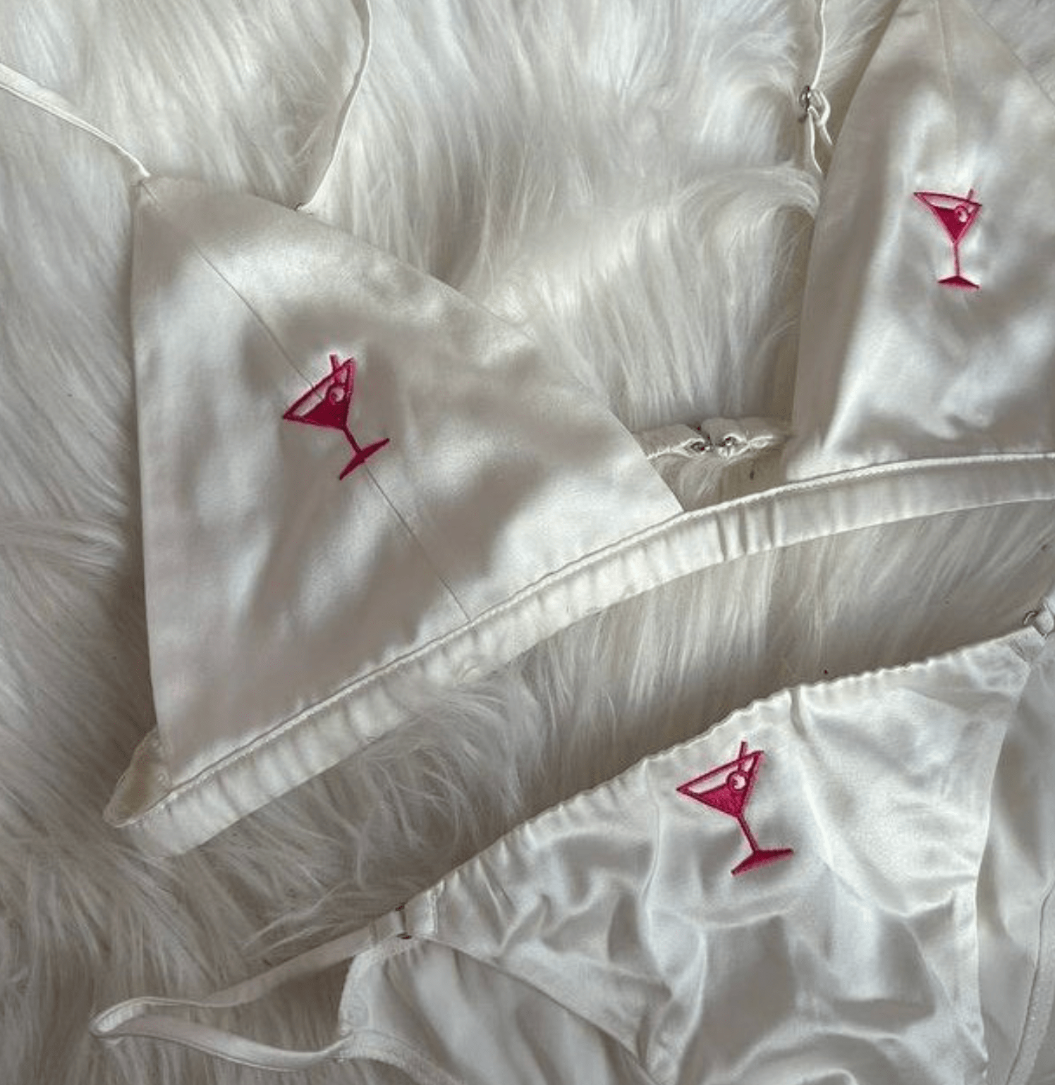 Satin lingerie set with pink martini glass embroidery on white faux fur background