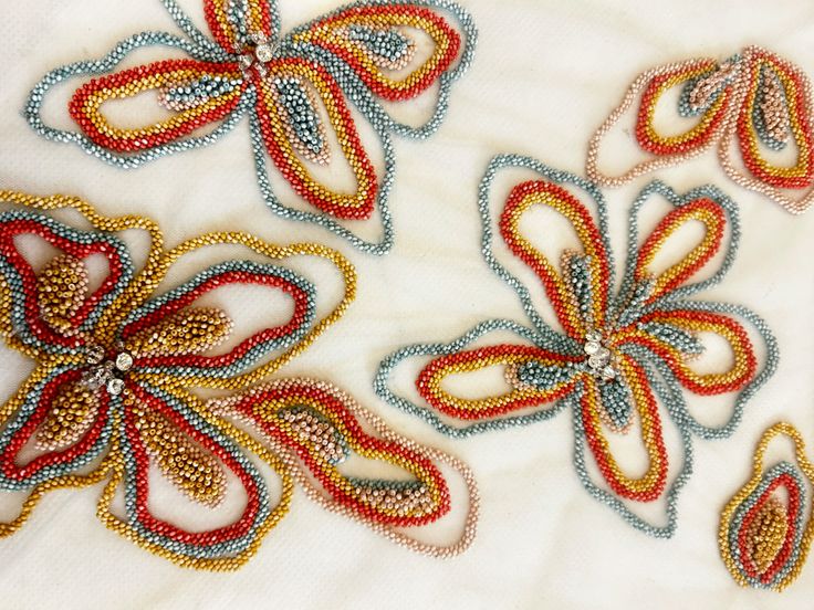 Colorful corded embroidery forming abstract flowers on sheer fabric.