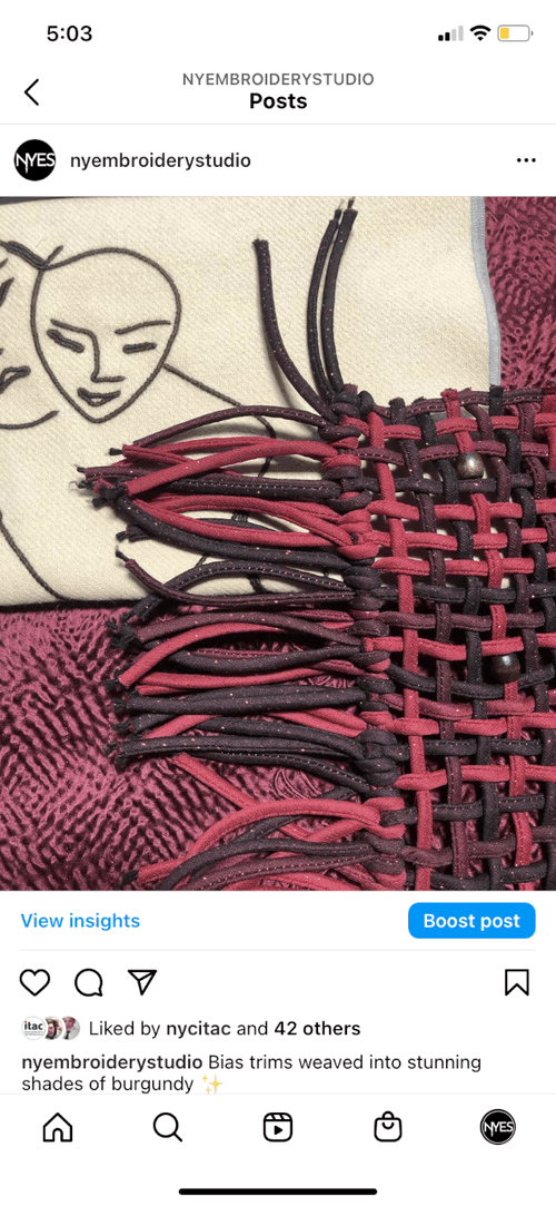 Red and black woven textile with pulled yarn detail.