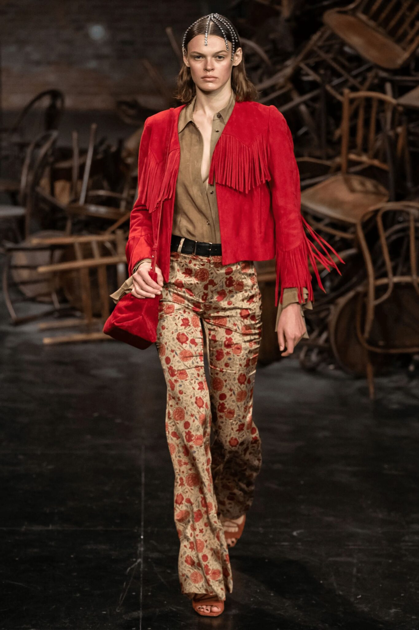 Runway model wearing red fringe jacket and floral trousers.