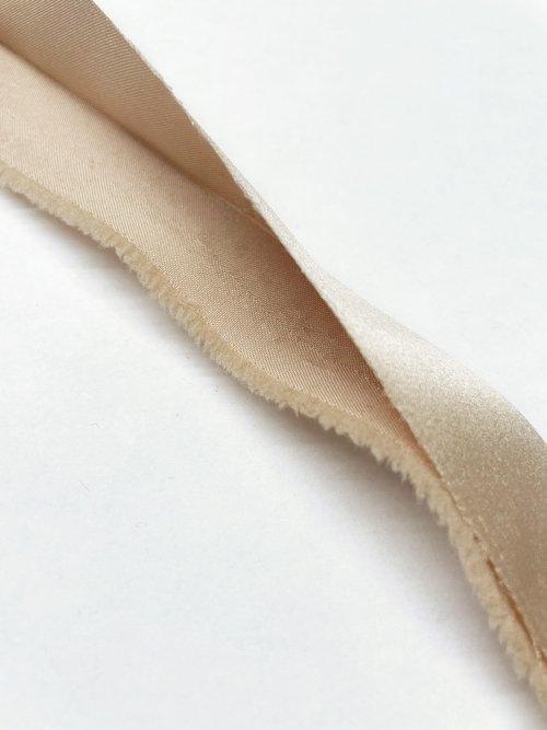 Beige binding ribbon folded on white background.