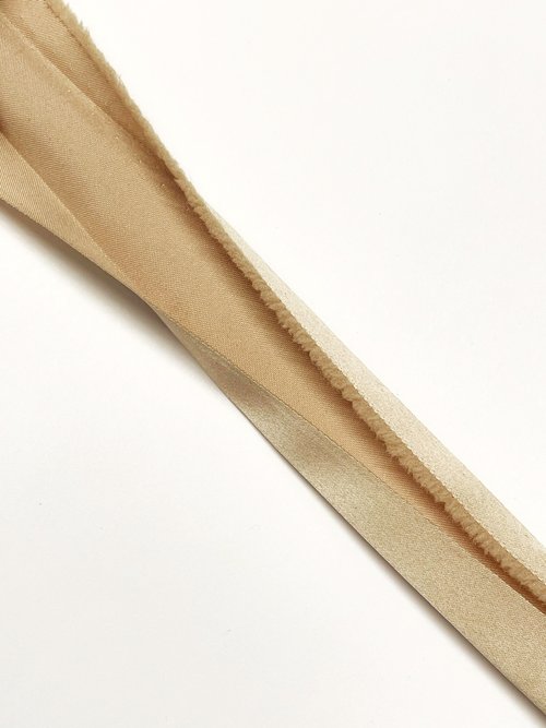 Beige binding ribbon folded on white background.