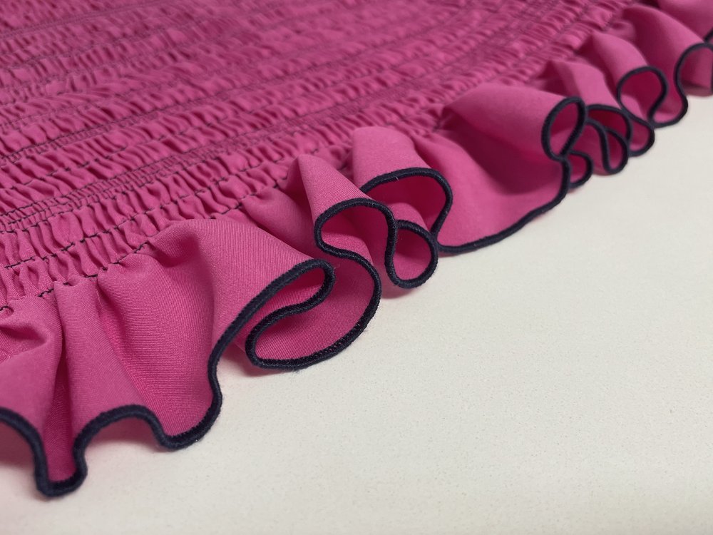 Close-up of pink ruffle trim with overlocked edge.