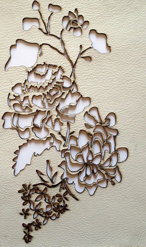 Embroidery of floral design in beige and white thread on leather.
