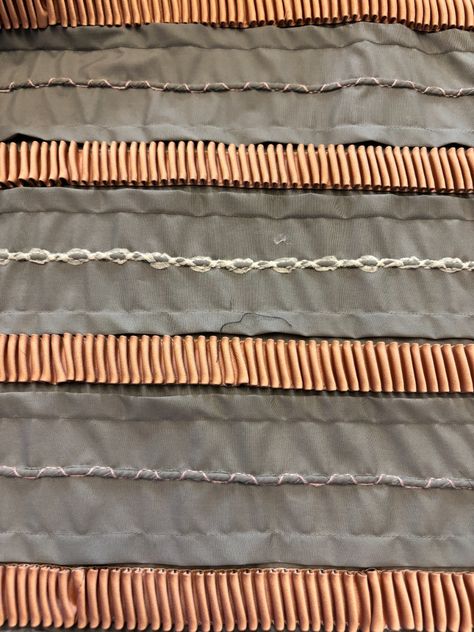 Intricate swirling quilting lines on taupe fabric using free-motion stitching.