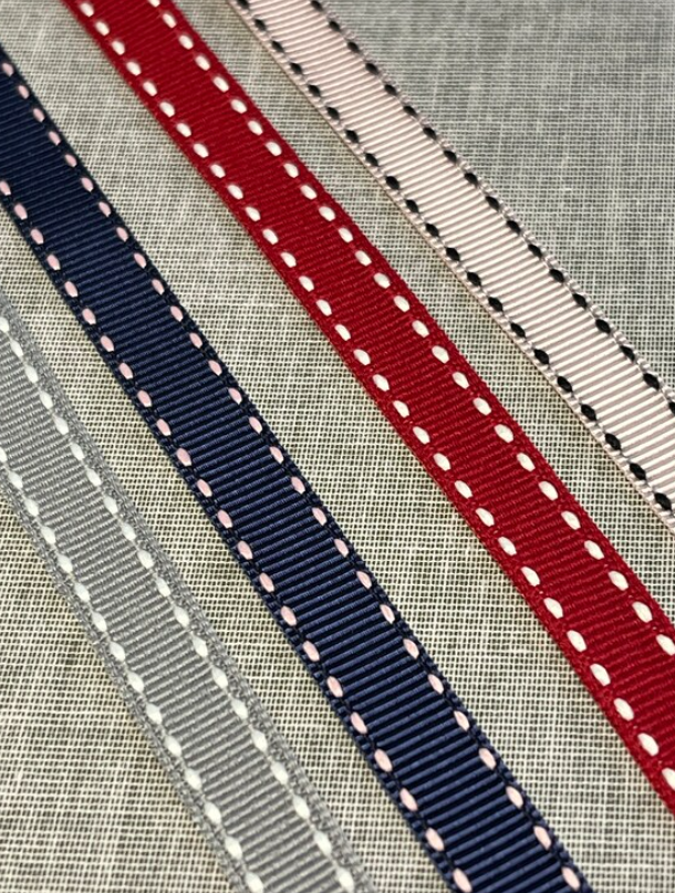 Grosgrain ribbon samples in red, navy, and beige with stitching.
