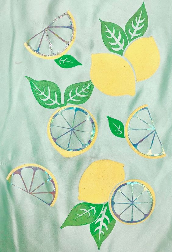 Embroidered yellow lemons with green leaves on light aqua fabric.