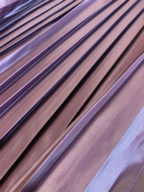 Iridescent pink pleated fabric with soft lighting.