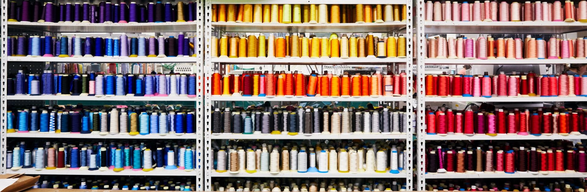 Floor-to-ceiling wall of organized spools arranged by color.