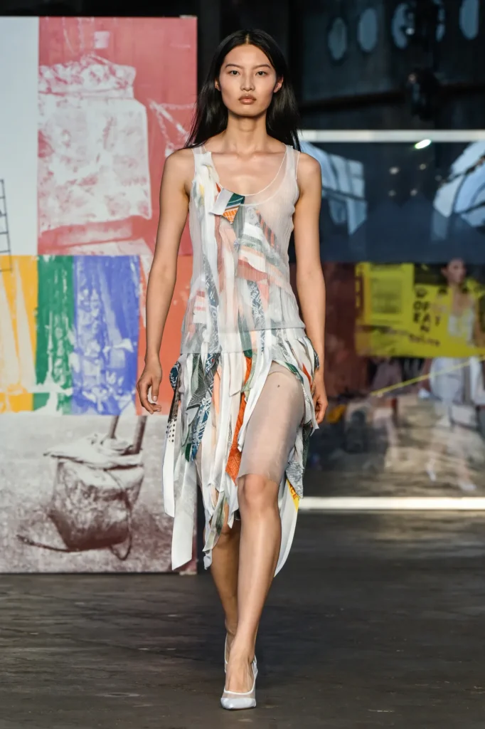 Runway shot of a model wearing Jason Wu SS26 patchwork collage dress, featuring bias-cut strips of silk and novelty fabrics in custom colorways, with raw-edge satin and sheer organza details.