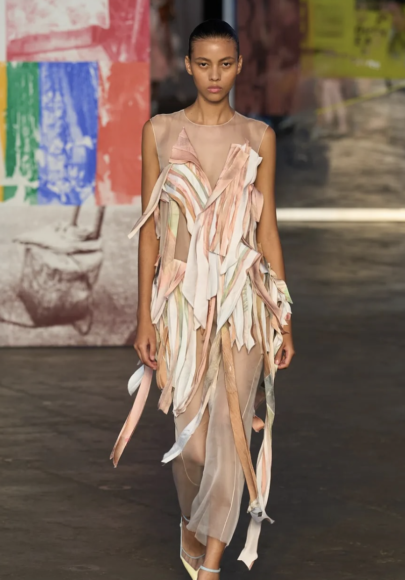 Runway shot of a model wearing Jason Wu SS26 patchwork collage dress, featuring bias-cut strips of silk and novelty fabrics in custom colorways, with raw-edge satin and sheer organza details.